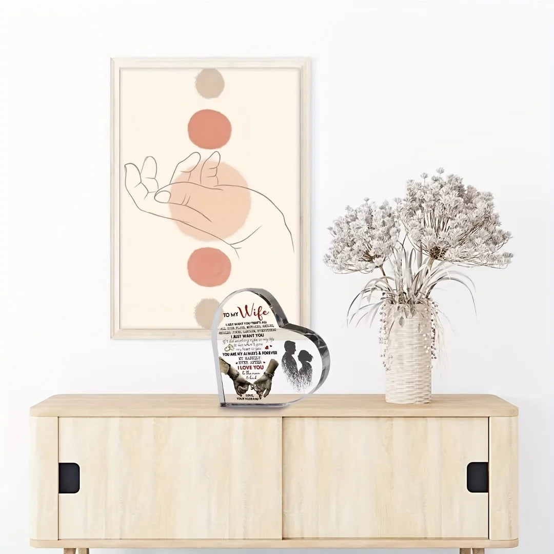 A framed artwork featuring a hand silhouette and circular shapes, displayed next to a heart-shaped acrylic decoration.