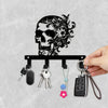 A black iron skull wall hook with a floral accent and several attached keys.