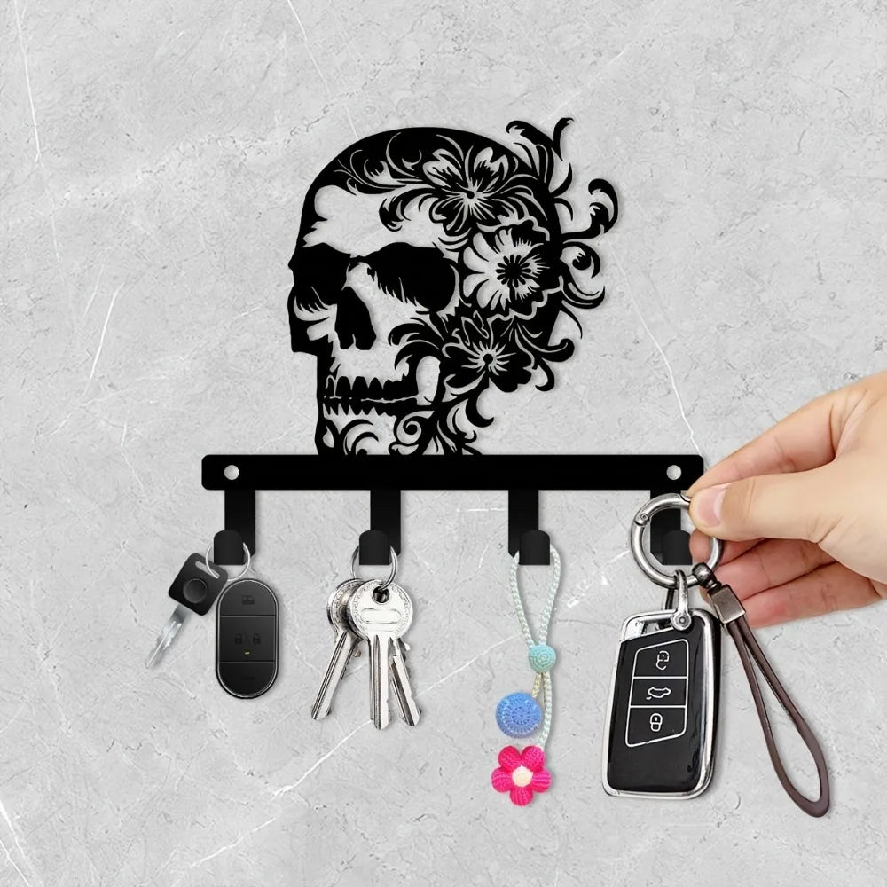 A black iron skull wall hook with a floral accent and several attached keys.