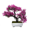 Un faux bonsaï réaliste avec des feuilles magenta vibrantes dans un pot rectangulaire blanc.