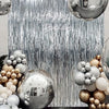 A silver and gold balloon and metallic foil fringe curtain backdrop for a birthday party.
