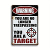 A vintage metal tin sign with a warning that reads You are no longer trespassing You are a target