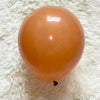 A single, round, translucent orange latex balloon resting on a white, fluffy surface.