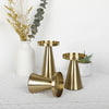 A set of three elegant gold metal candle holders with conical bases and wide rims, displayed on a white surface.