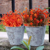 Un bouquet de fleurs d'automne et d'Halloween artificielles dans des pots en métal galvanisé