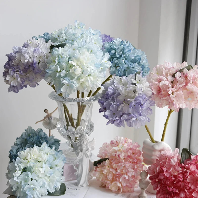 A floral arrangement featuring various shades of hydrangea blossoms in purple, blue, white, and pink.