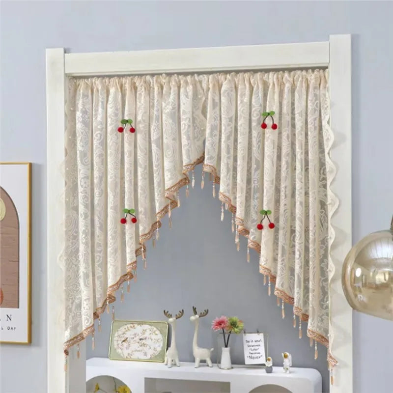 A sheer lace door curtain with fringe and a scalloped top is displayed in a white frame.