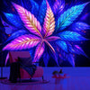 A vibrant neon cannabis leaf tapestry hangs against a dark blue background, illuminating a pink chair and wooden floor.