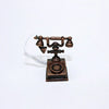 A vintage rotary desk phone miniature decor with a brass body and white cord.