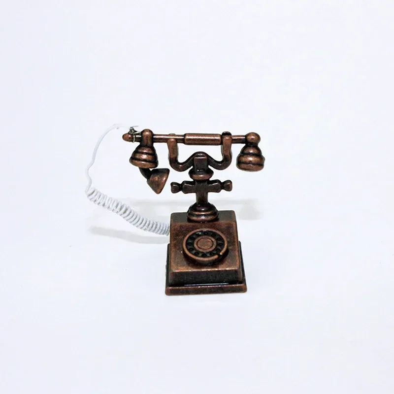 A vintage rotary desk phone miniature decor with a brass body and white cord.