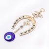 Gold horseshoe amulet with blue eye charm and elephant pendant on a chain