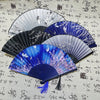 A collection of elegant vintage Chinese folding hand fans in various shades of blue and black displayed on a light patterned 