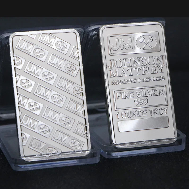 A silver bullion bar replica labeled Johnson Matthey Fine Silver 999 1 ounce Troy inside a clear plastic case.