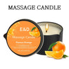 A massage candle in a black jar with an orange flame and sliced orange fruit.