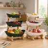 A wooden fruit basket stand holds various fresh fruits like grapes, apples, and berries in green and white bowls.