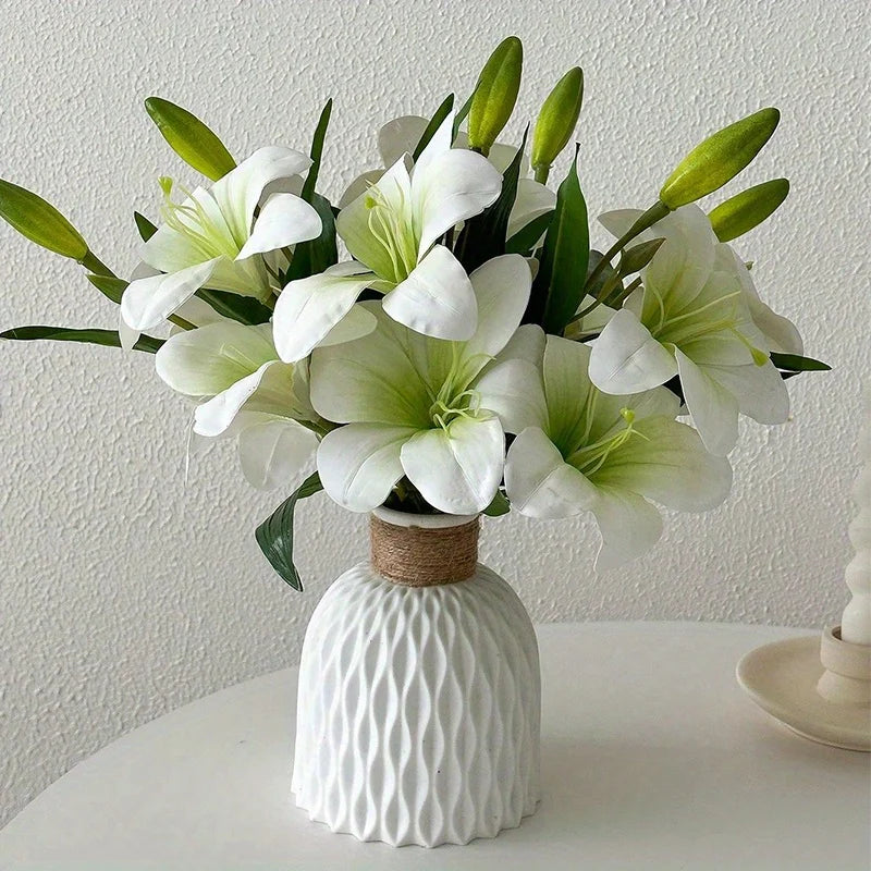 A bouquet of white artificial lilies with green buds in a white textured vase.