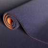 A roll of dark blue artificial grass carpet with an orange accent, shown in a close-up view.