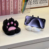 A black cat paw silicone phone stand with a pink accent resting on a white surface.