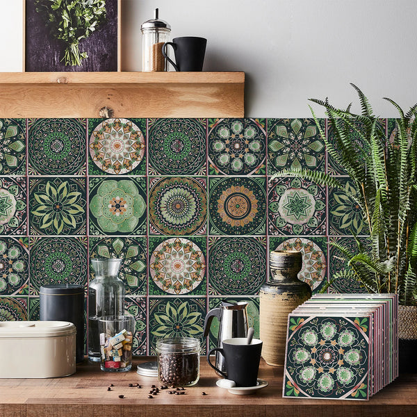 A close-up of self-adhesive tile wall stickers featuring intricate green and beige floral patterns on a wooden surface.