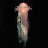 A glowing jellyfish lantern lamp with translucent pink and green fibers suspended against a black background.