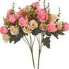 A bouquet of realistic silk rose flowers in shades of pink, peach, and cream with green leaves.