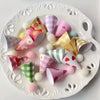 A collection of colorful mini birthday cake toppers in various patterns and colors arranged on a white platter.