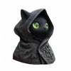 A dark, textured statue of a cat wearing a hooded cloak with glowing green eyes.