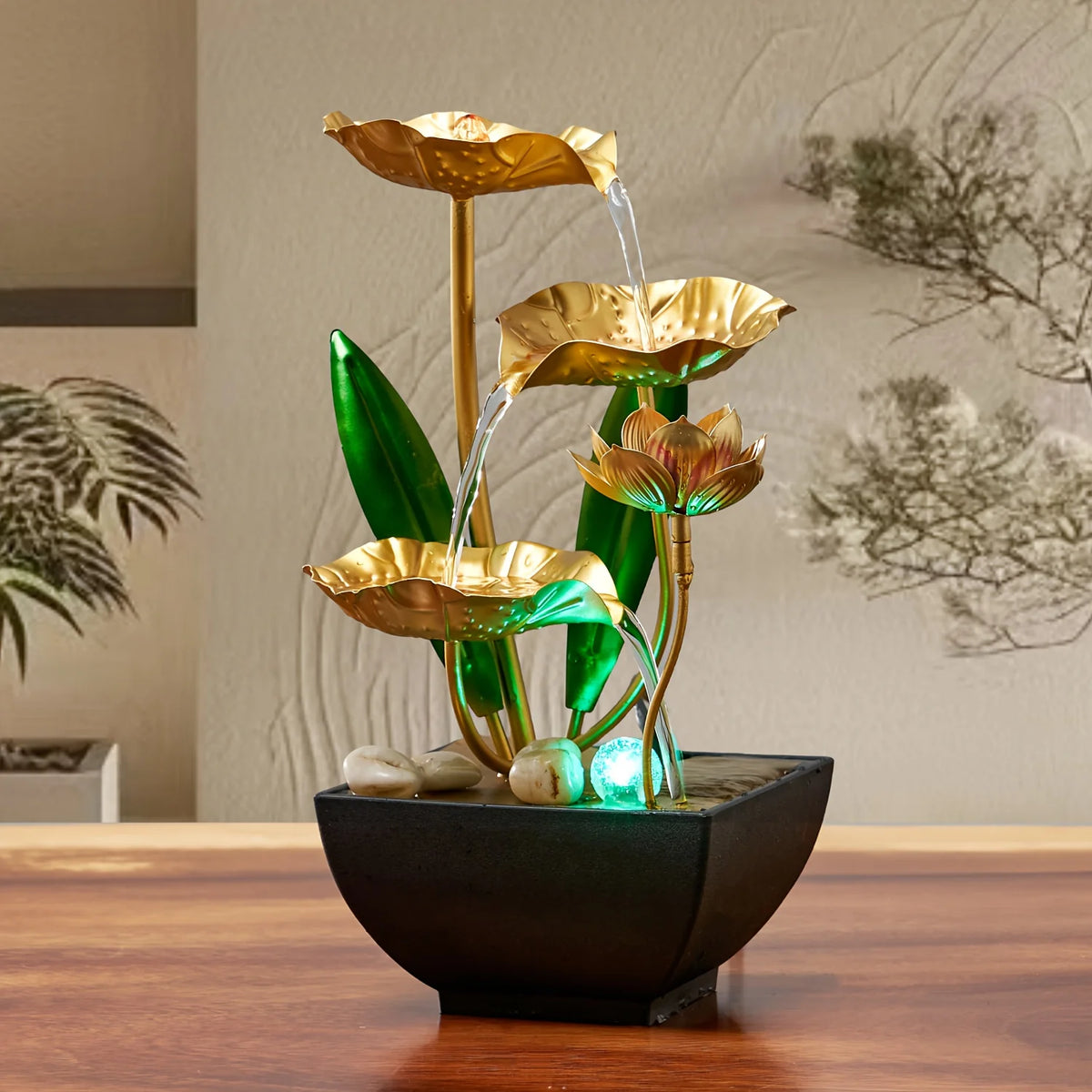 A golden tabletop fountain featuring leaves and water spouts, set in a black bowl.