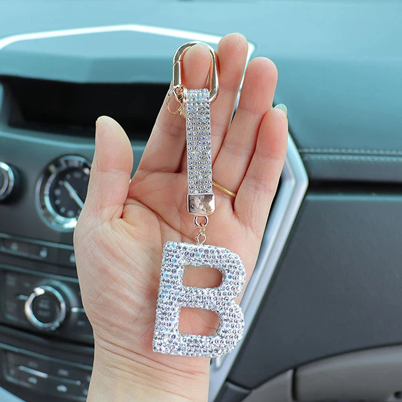 A hand holds a crystal letter keychain charm with a silver loop and a sparkling letter B.