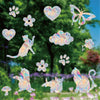 Rainbow suncatcher window stickers featuring cat and butterfly designs scattered over a green outdoor background.