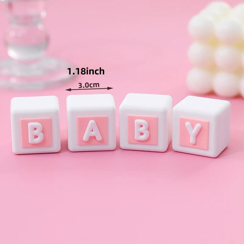 Four white baby blocks with pink letters B A B Y arranged in a row on a pink background
