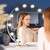 A woman is looking into a round, dimmable LED vanity mirror while applying makeup.