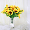 A bouquet of bright yellow artificial sunflowers in a clear glass vase against a white background.