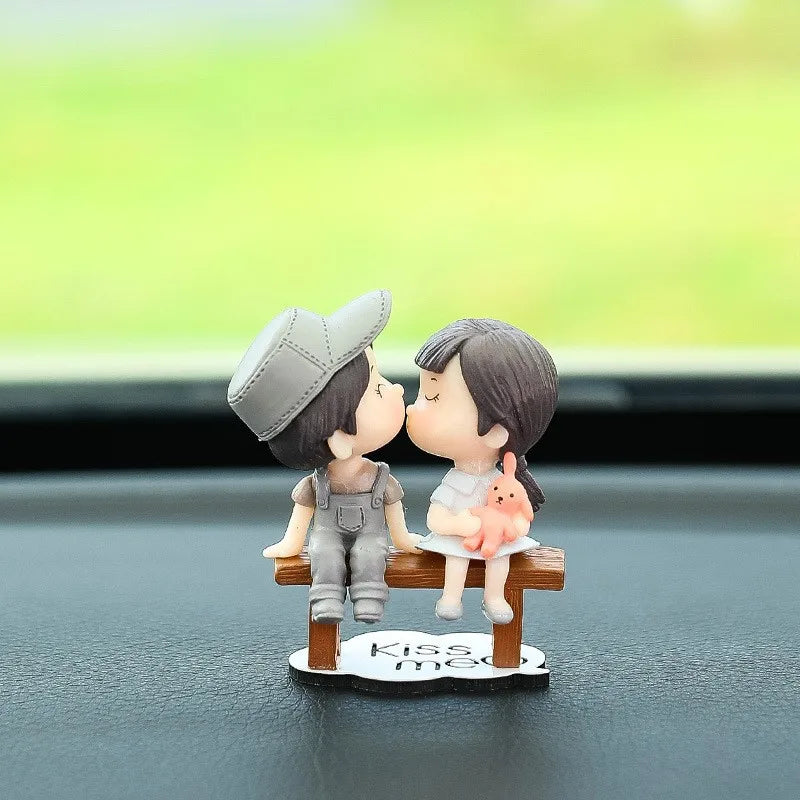 A small figurine of a couple kissing, with a pink balloon, displayed on a dark surface.