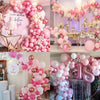 A collection of pastel pink and white latex balloons with metallic confetti accents arranged in decorative arches and cluster