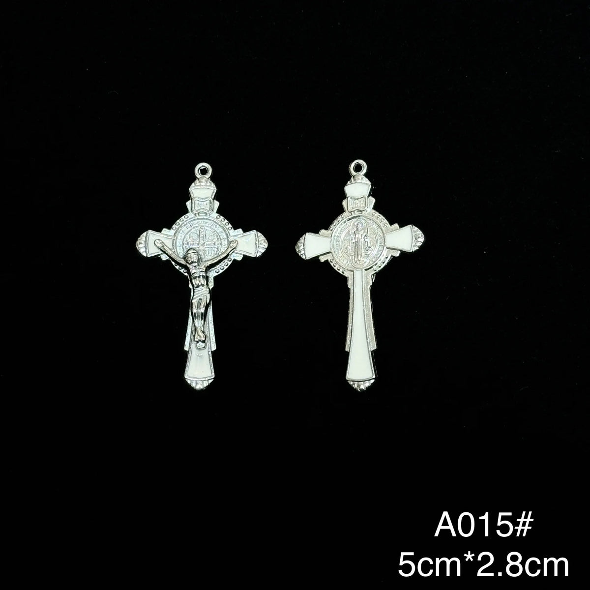 A pair of silver crucifix pendants featuring a depiction of Christ and St. Benedict with an enamel finish.