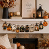 A vintage wooden Halloween flag set featuring pumpkins, ghosts, and moons displayed on a mantelpiece.