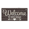 A rustic wooden hanging sign with white script that reads Welcome to our home and features a heart-shaped arrow design.