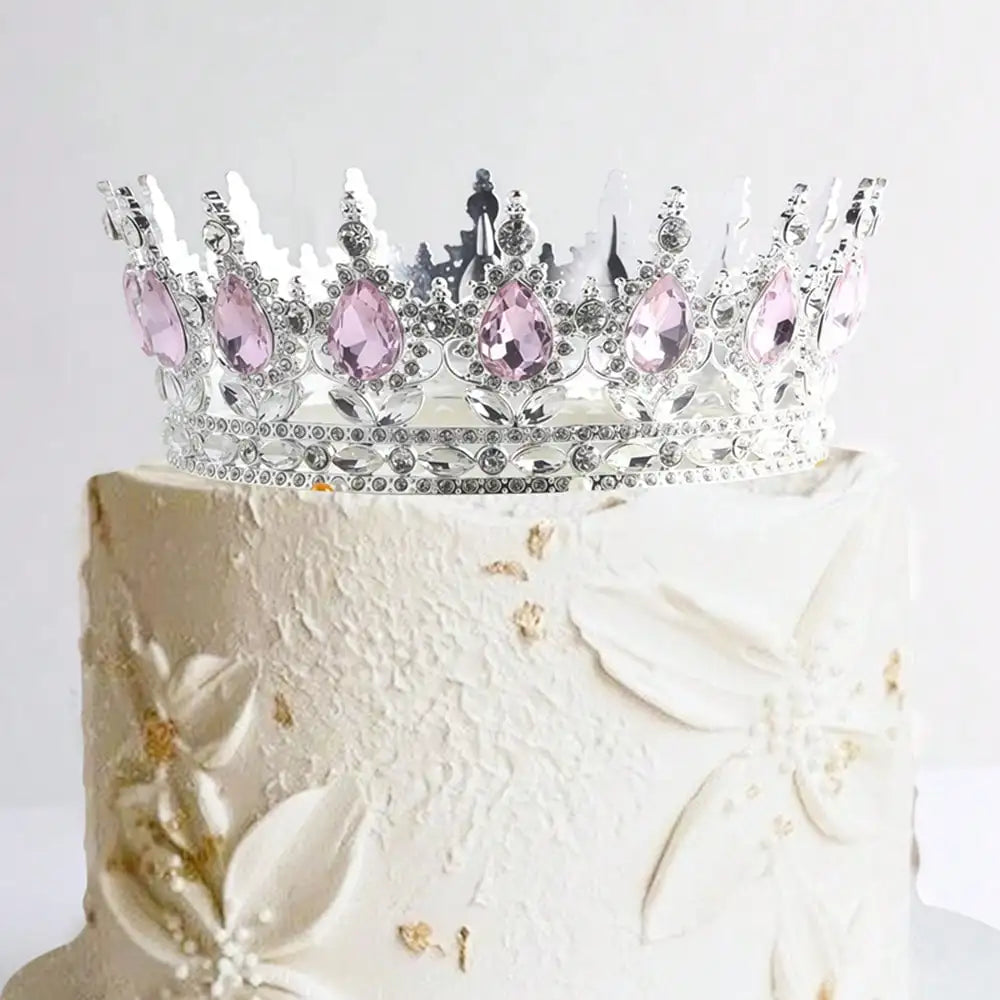 A white cake decorated with a sparkling crystal rhinestone crown topper.
