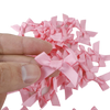 A hand holds a set of pink satin bow cupcake toppers for parties.