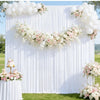 Elegant white pleated drapery backdrop decorated with pink and white floral garlands for weddings and parties