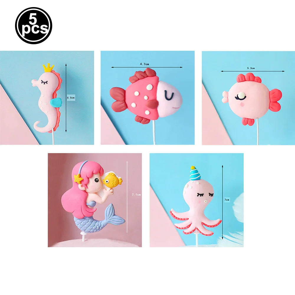A set of five pink and white ocean animal cake toppers including a crab, turtle, octopus, whale, and starfish.