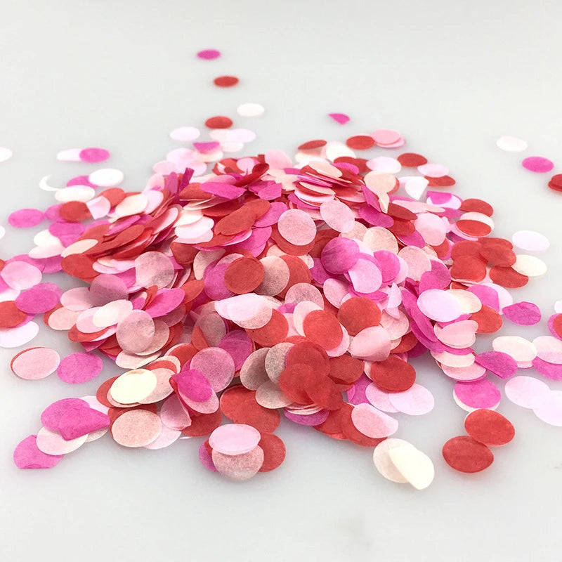 A pile of multicolor paper confetti in shades of pink and red scattered on a white surface.
