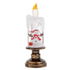 A clear glass candle in the shape of a snowflake with a gold flame on top, mounted on a brass base.