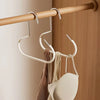 A set of metal hat storage hooks hanging from a wooden rod on a door.