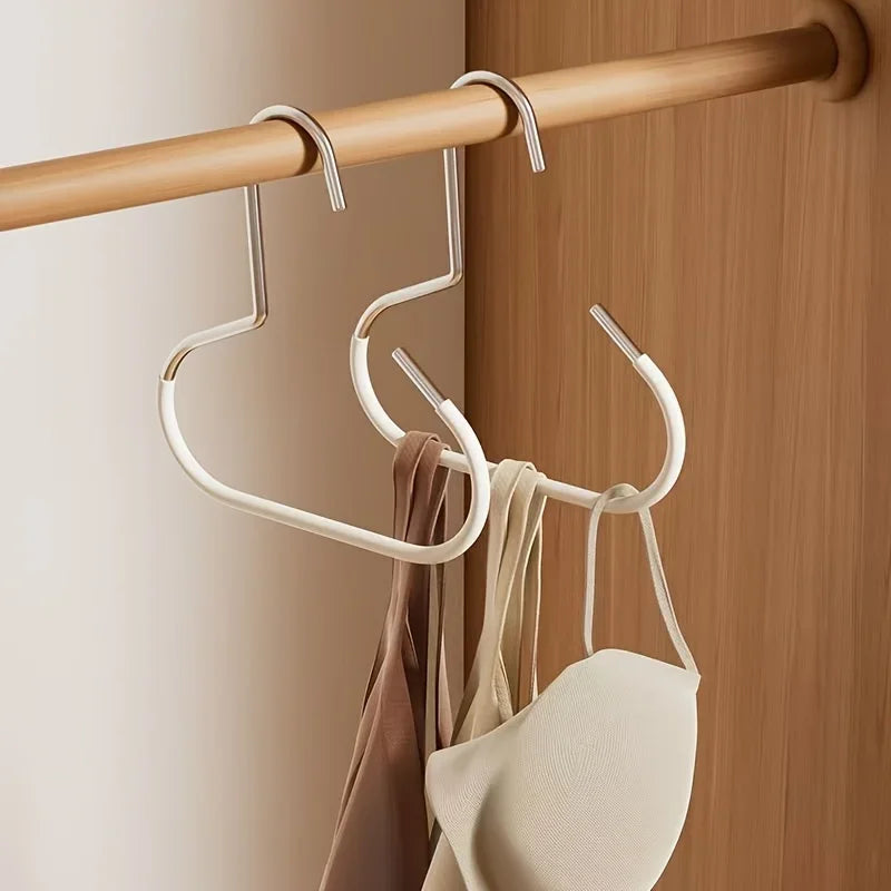 A set of metal hat storage hooks hanging from a wooden rod on a door.