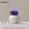 A purple amethyst crystal resting on a white, bean-shaped decorative stone.