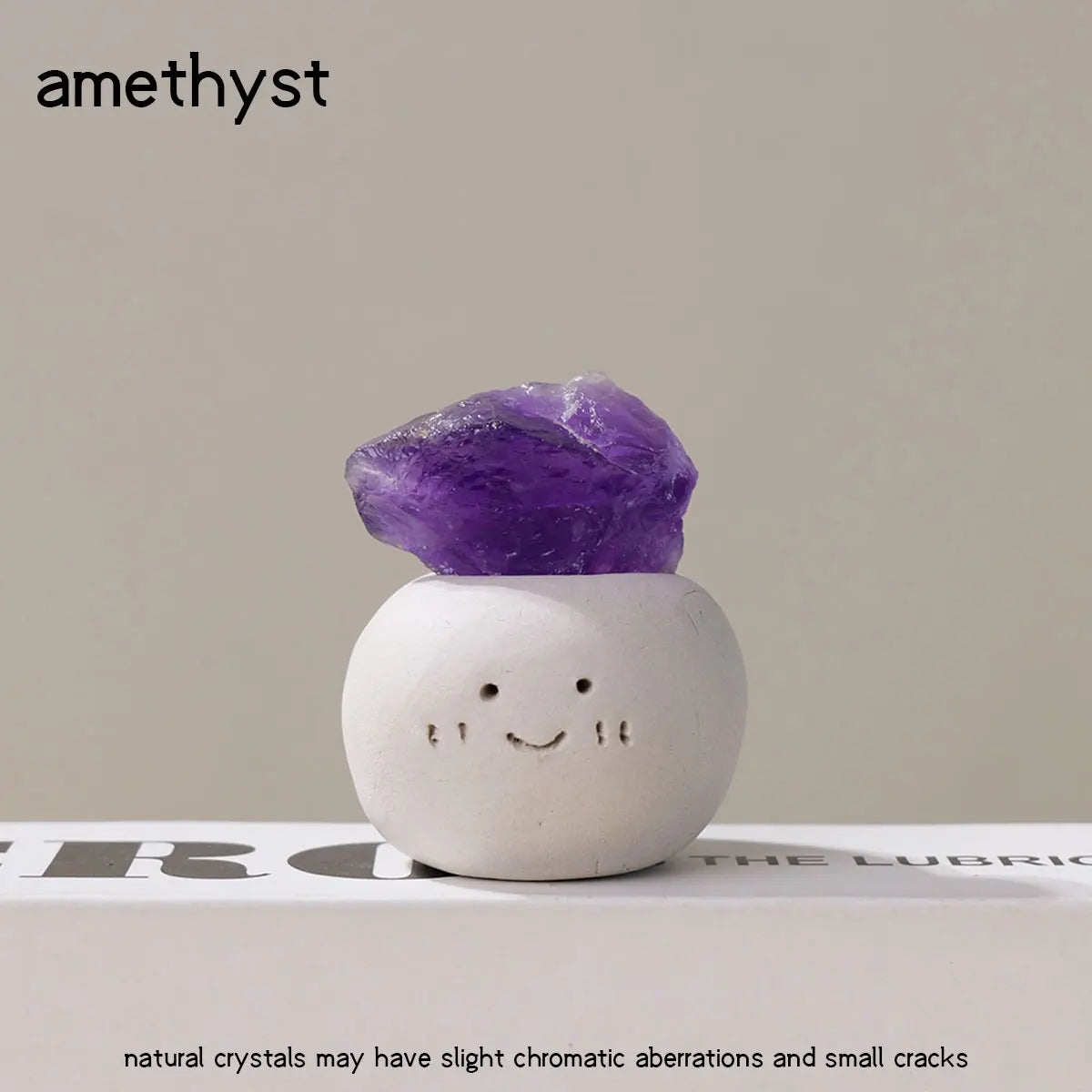 A purple amethyst crystal resting on a white, bean-shaped decorative stone.