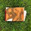 A folded California State Flag in brown and white patterns rests on green grass.