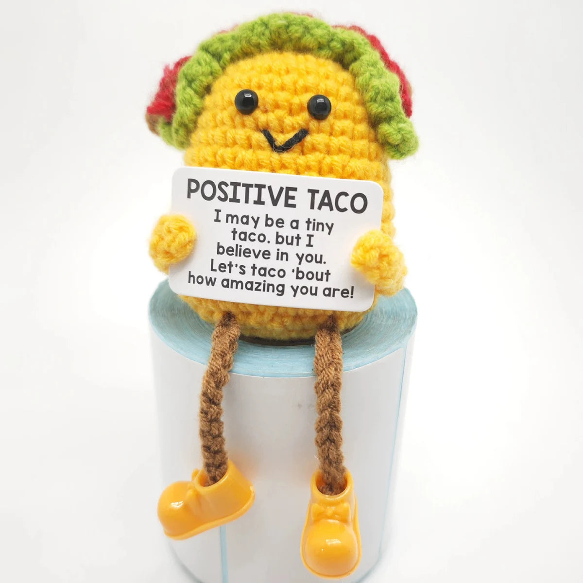 Handmade crochet potato doll with green and red hair holding a card that says Positive Taco